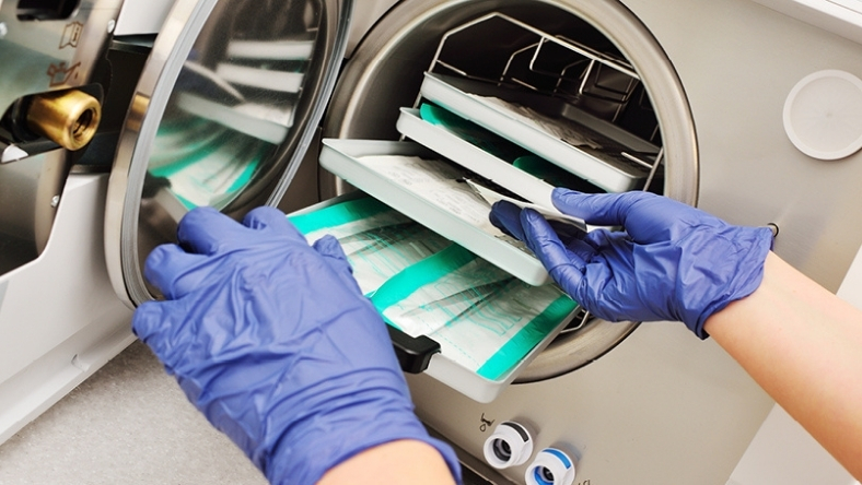 Healthcare worker loading medical instruments into a sterilization machine